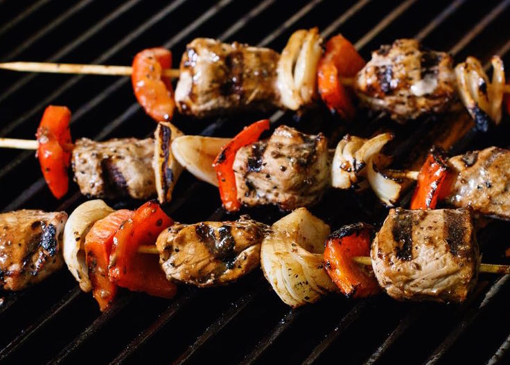 3 meat kebobs with pepper and mushroom on a grill