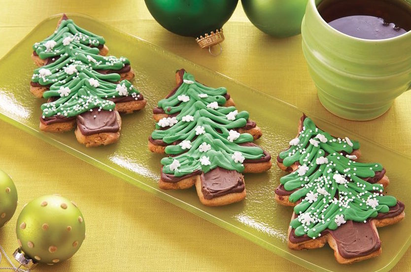 tree cookies with green frosting on a light green serving platter