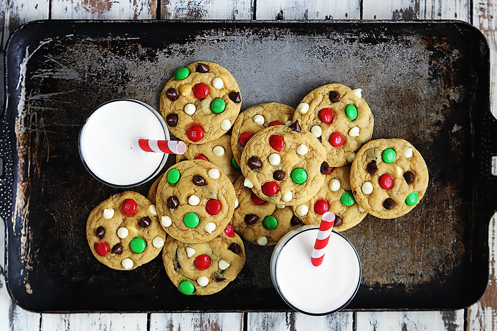 a cooking tray with m&m candied cookies on it, with 2 glasses of milk