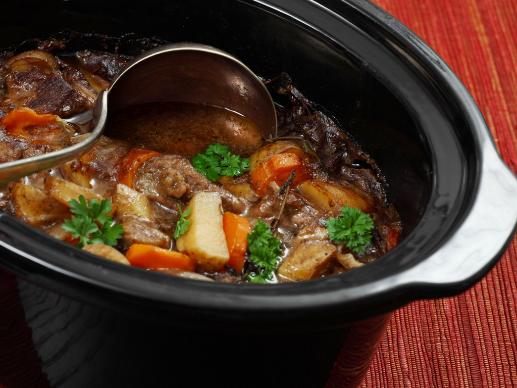 slow cooker with stewed meat, carrots, and potatoes