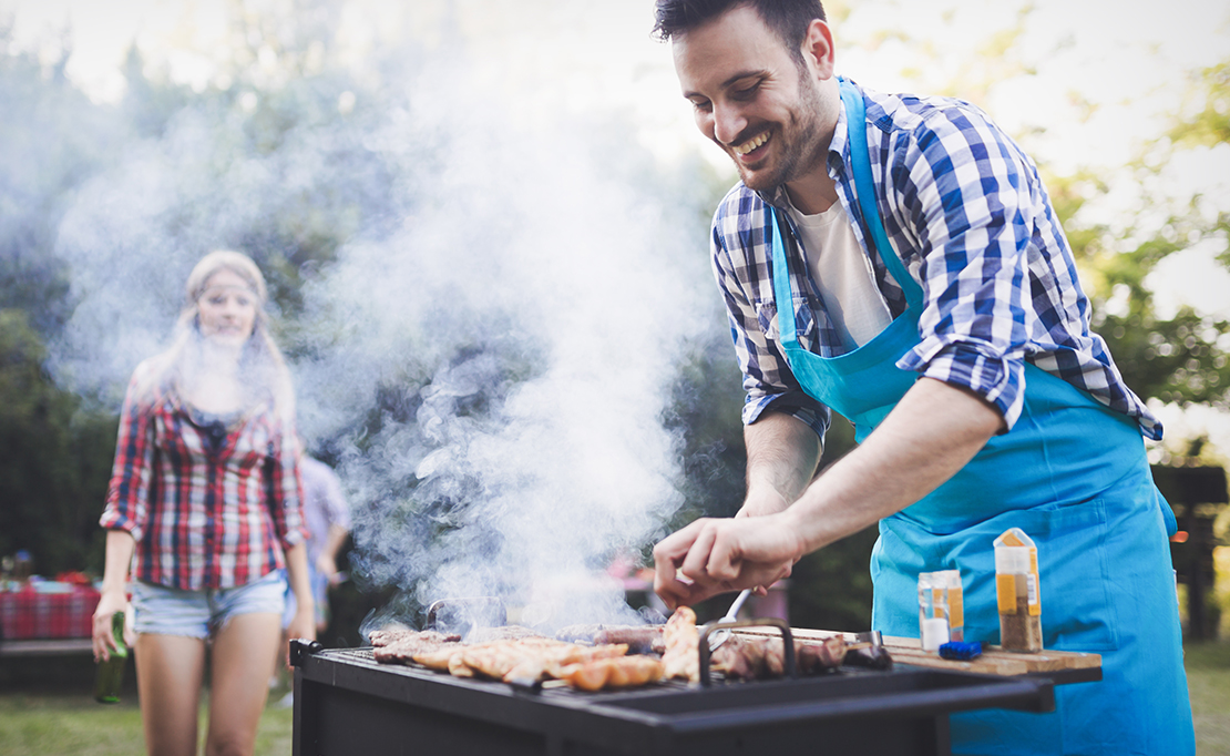 a man smiling and grilling