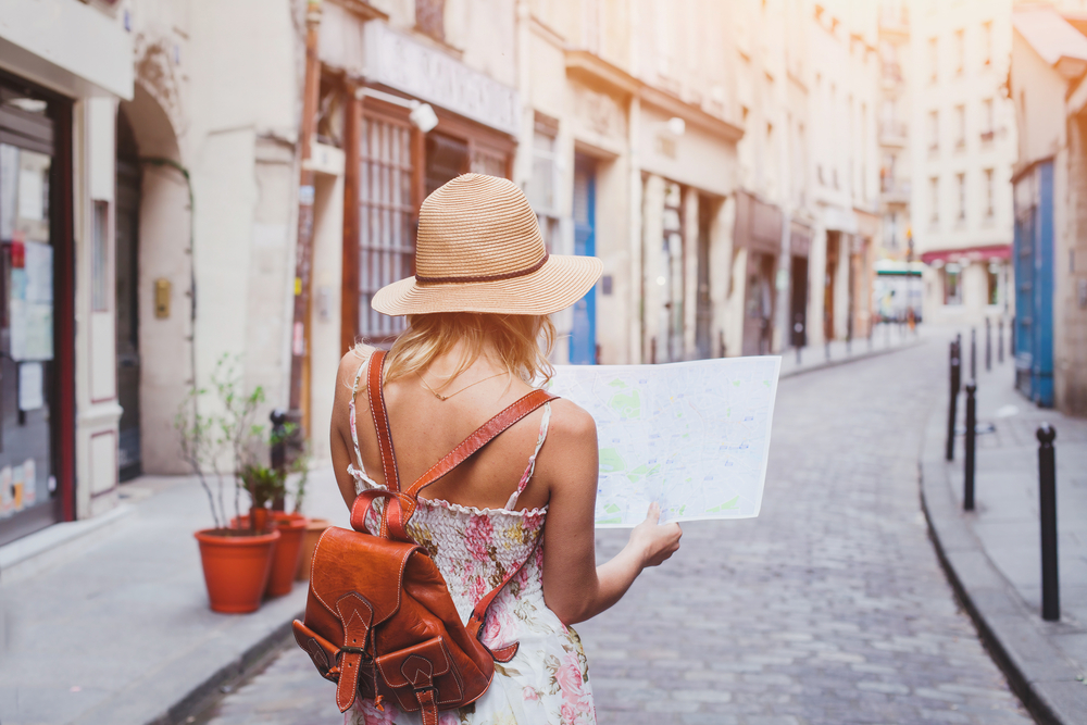 A woman looks at a map on an unfamiliar city cobblestone streets