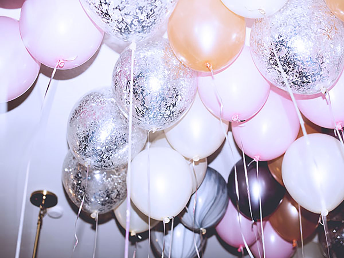 A dozen balloons in different colors llike gold, pink, black, sparkle silver
