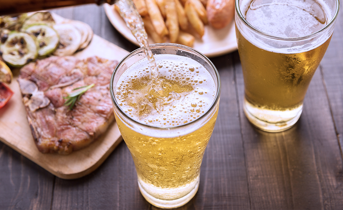 Light beers sit on a table by steak and fries