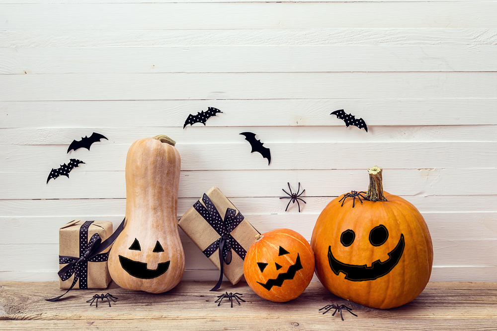 various gourd Jackolanterns smile on a doorstep surrounded by paper bats