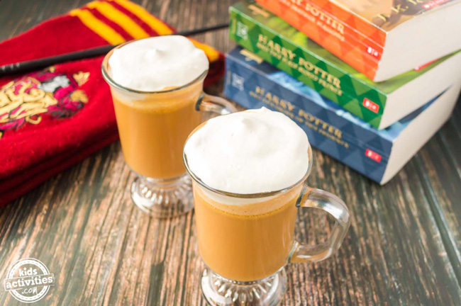 Two frothy orange glasses of butterbeer