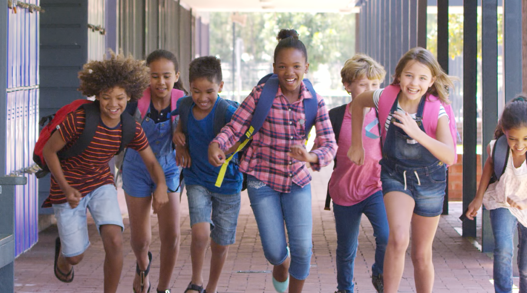 Children running through a school hallway, smiling